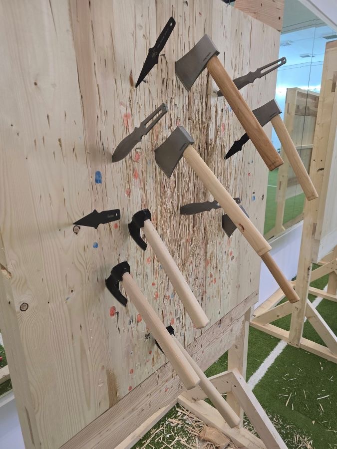 Topoare, cuțite și shuriken înfipte în ținta de lemn de pin